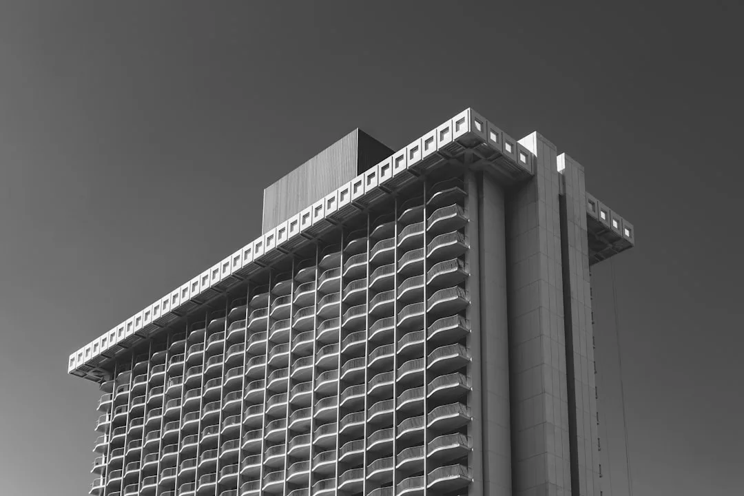 Fotografía en blanco y negro de un moderno rascacielos con múltiples balcones curvos, que capta la esencia del lujo en Mallorca bajo un cielo despejado.