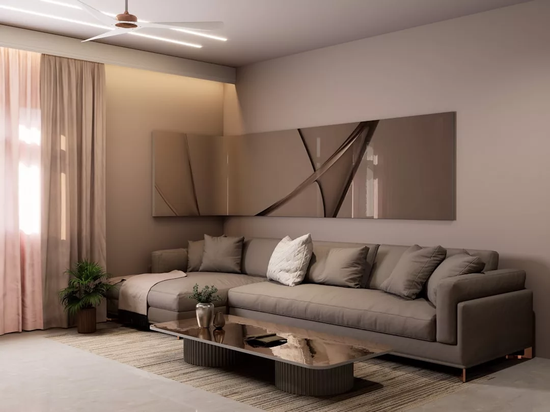 Una moderna sala de estar con un gran sofá seccional gris, arte abstracto en la pared, una mesa de centro baja, plantas en macetas y paredes de color beige está decorada con un estilo de lujo inspirado en Mallorca, complementado con una suave iluminación natural y empotrada.