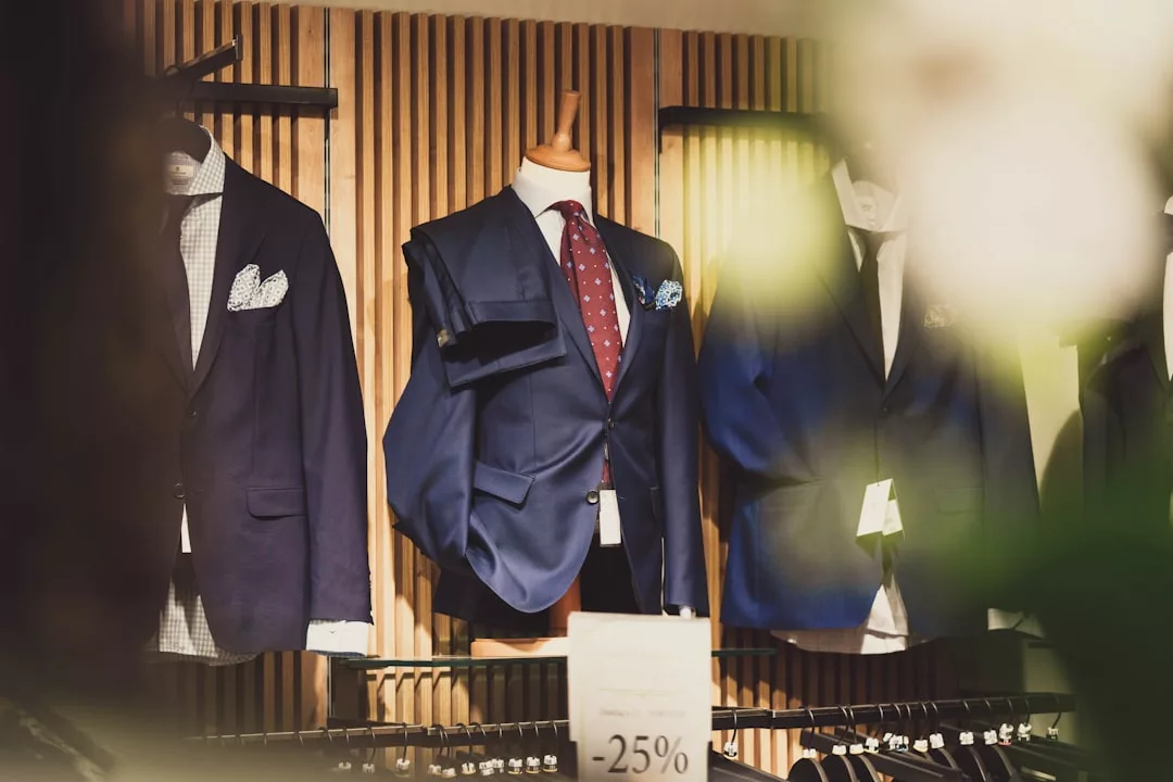 Un escaparate con trajes de hombre en maniquíes y perchas destila lujo, con un cartel que indica un descuento del 25%, perfecto para elevar tu estilo mallorquín.