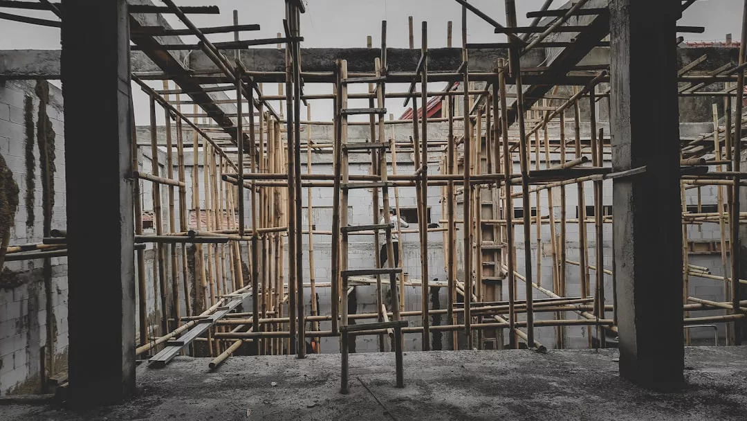 Andamios de bambú instalados en el interior de un edificio de hormigón en construcción en Mallorca, con paredes grises y un suelo inacabado que insinúan un futuro lujo.