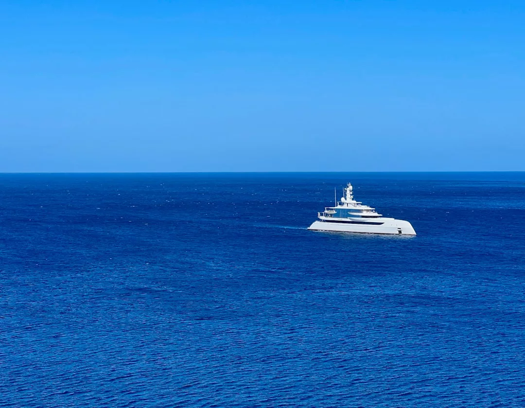 Un yate blanco de lujo navega por un mar tranquilo y azul profundo bajo un cielo azul claro cerca de Mallorca.