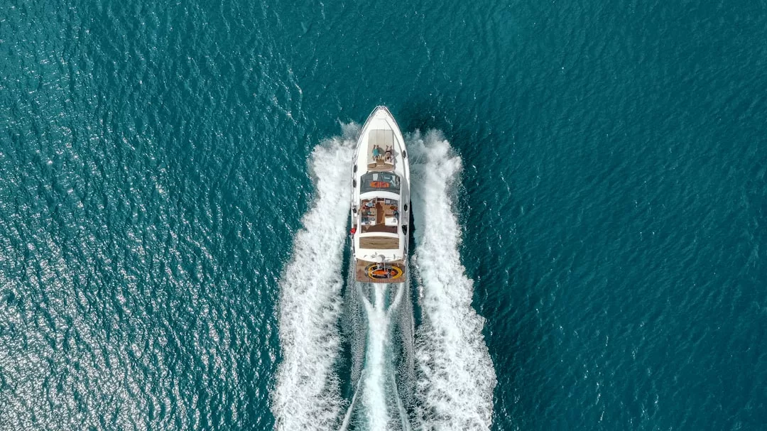 Vista aérea de una lancha motora surcando a toda velocidad las aguas azules de Mallorca, dejando tras de sí estelas blancas: una auténtica escena de lujo.