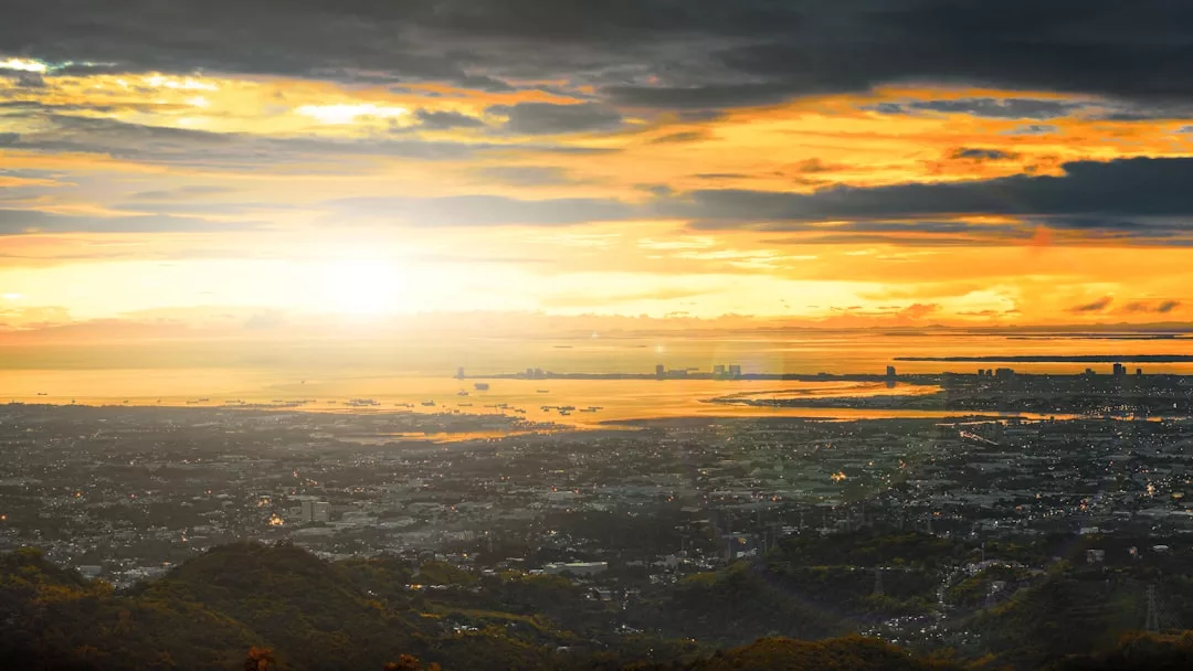 Se muestra un paisaje urbano de Mallorca con edificios y agua al atardecer, el cielo iluminado en tonos naranjas y amarillos con nubes oscuras por encima, creando una escena de lujo moderno con un dramático telón de fondo.