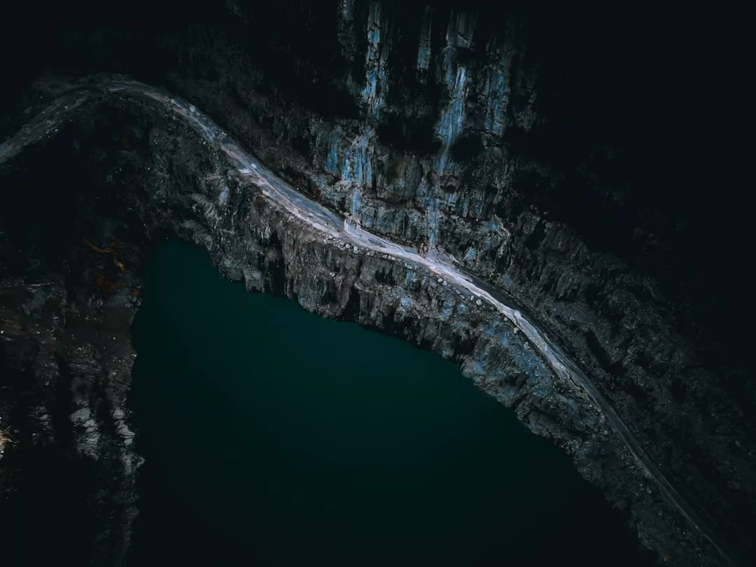 Una carretera estrecha y sinuosa discurre por el borde de un escarpado acantilado rocoso sobre aguas de color verde oscuro en Mallorca, ofreciendo una visión del lujo de la isla desde arriba.