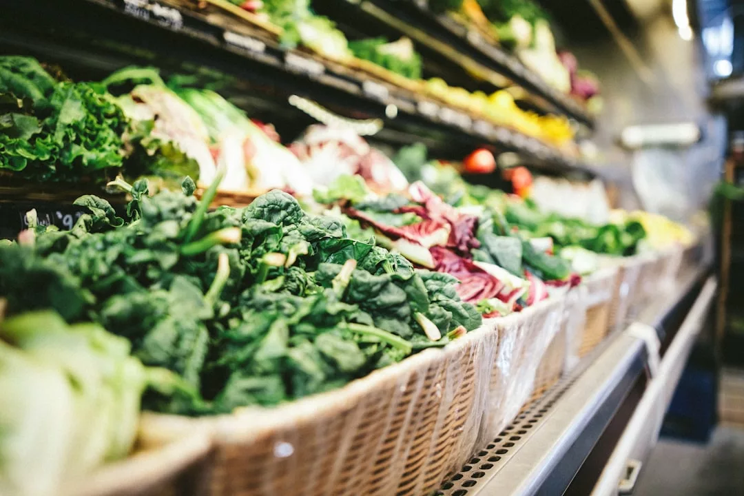 Cestas de verduras de hoja verde y otros productos se exhiben en los estantes de una sección de productos de una tienda de comestibles, ofreciendo un toque de lujo y los frescos sabores de Mallorca.