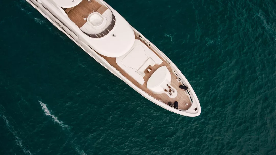 Vista aérea de un lujoso yate blanco surcando las profundas aguas azules de Mallorca, encarnando puro lujo.