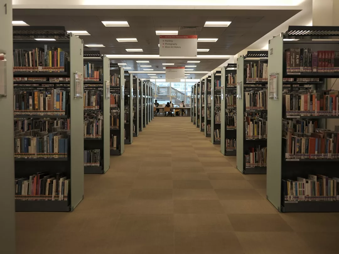Hileras de estanterías se alinean en un espacioso pasillo de la biblioteca, exudando un aire de lujo, con algunas personas sentadas y leyendo en mesas al fondo - un inesperado retiro en el corazón de Mallorca.