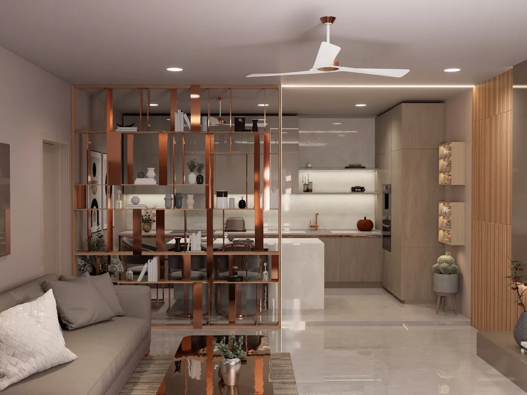 Moderno salón y cocina de planta abierta en Mallorca con sofá seccional, mesa de centro de cristal, tabique decorativo de estanterías y decoración minimalista de lujo en tonos neutros.