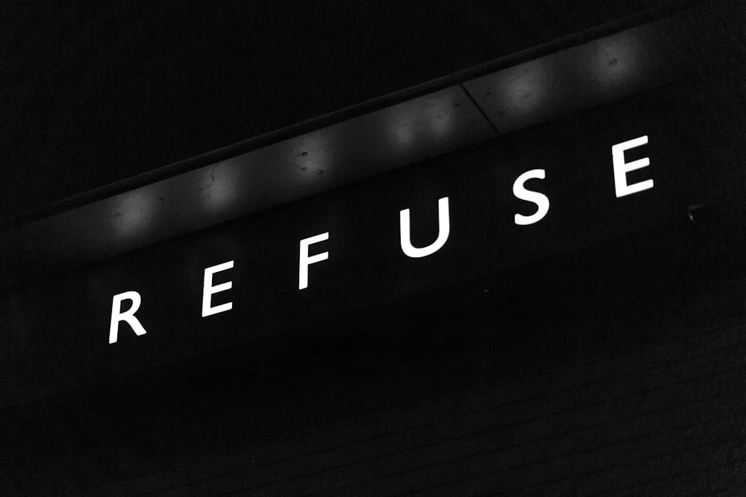 Un letrero negro con la palabra "REFUSE" iluminada en mayúsculas blancas sobre un fondo oscuro, evocando un aire de lujo que recuerda a la exclusiva vida nocturna de Mallorca.