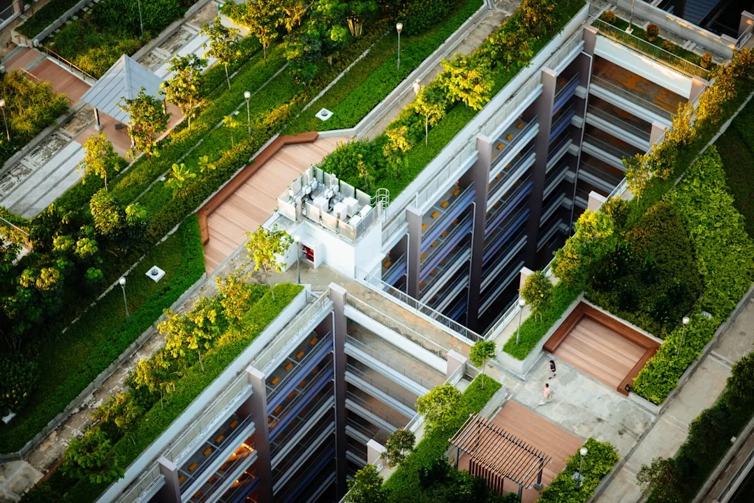 Vista aérea de un complejo de apartamentos de lujo en Mallorca, con tejados verdes, terrazas y caminos rodeados de árboles y jardines paisajísticos.