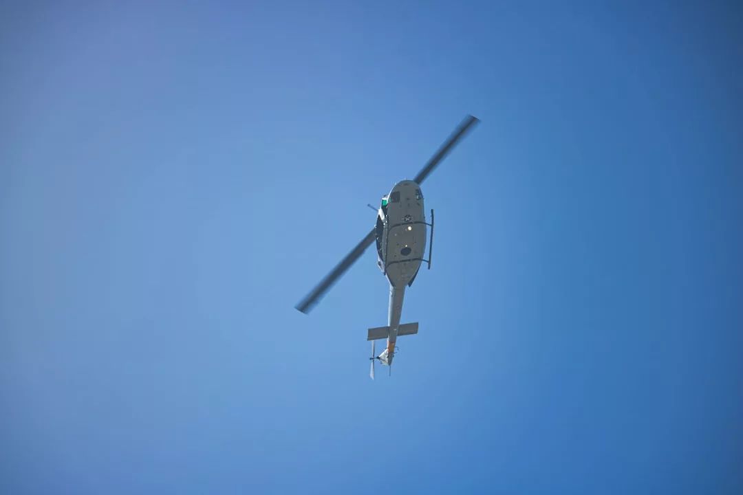 Un helicóptero sobrevuela un cielo azul claro, visto directamente desde abajo: un toque de lujo perfecto para un día soleado en Mallorca.