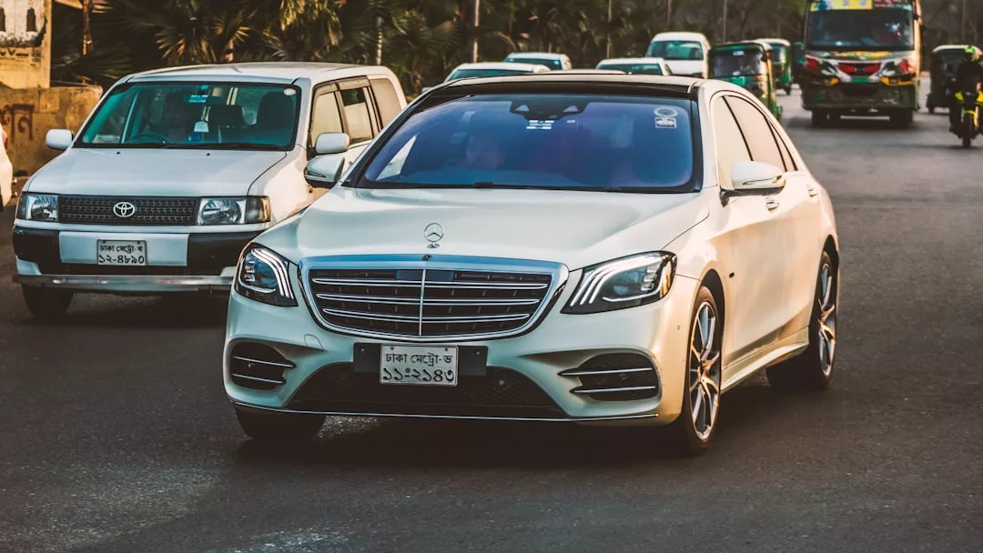 Un Mercedes-Benz sedán blanco, que destila lujo, circula por una calle de la ciudad de Mallorca, rodeado de otros vehículos a la luz del día.