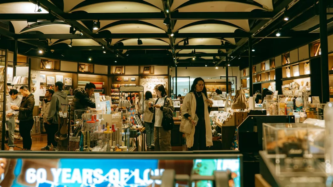 La gente curiosea y compra dentro de una tienda Lujo bien iluminada en Mallorca, con estanterías repletas de diversos artículos mientras varios clientes hacen cola en el mostrador.