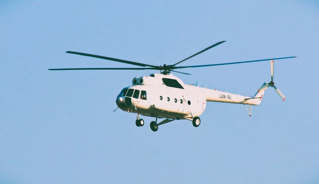 Un helicóptero blanco con un diseño de dos rotores se eleva grácilmente sobre el cielo azul, ofreciendo un toque de lujo mientras sobrevuela Mallorca.